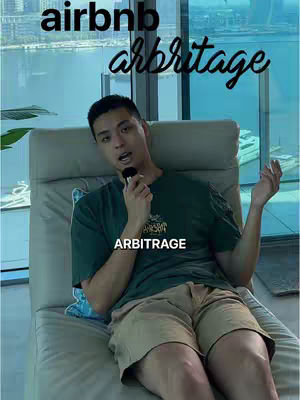 A man in a green t-shirt and khaki shorts is seated on a beige lounge chair with a cityscape visible through a window behind him. Text overlays read 'airbnb' and 'arbitrage'.