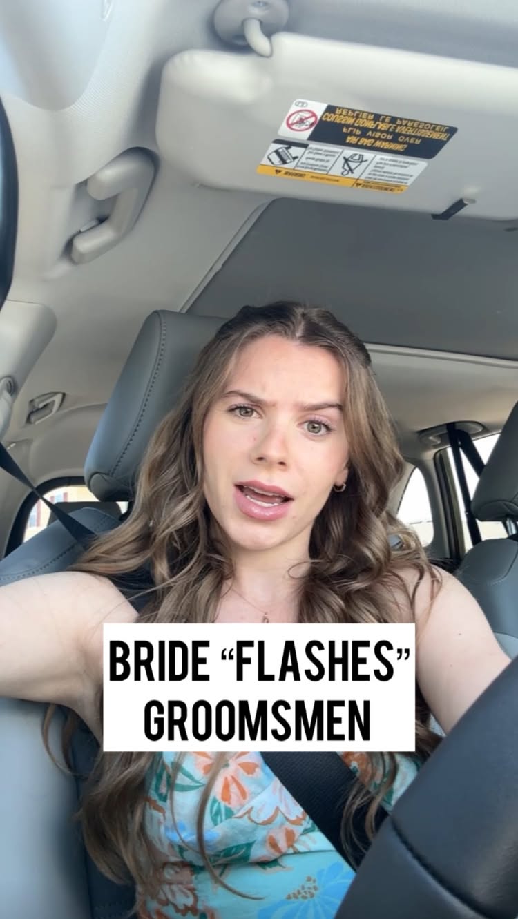 A woman is sitting in a car, looking at the camera and speaking. Text overlayed on the image reads, "BRIDE 'FLASHES' GROOMSMEN". She is wearing a floral top.