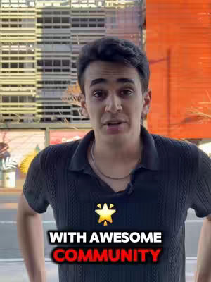 A young man with dark hair stands in front of a blurred outdoor background. He is wearing a dark polo shirt and a silver chain. The text overlay reads 'WITH AWESOME COMMUNITY' in a white font with a red outline, a gold star is in center. The background has a tall building on the left and shades of orange.