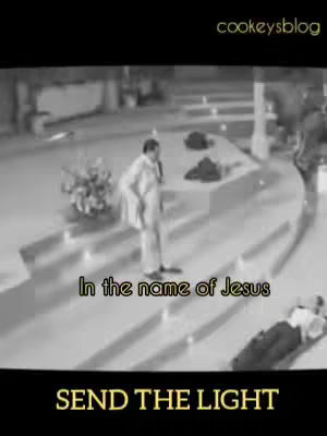 A black and white image taken in a church. A man in a white suit is standing, speaking into a microphone on the steps. In the center, there's text superimposed.