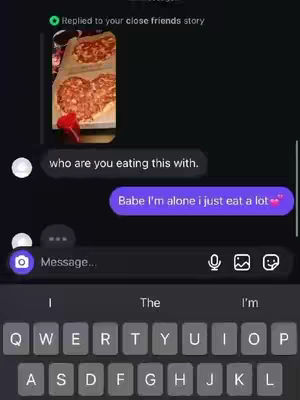 A screenshot of a phone conversation. The background is dark purple. The top of the screen has a notification that says "Replied to your close friends story". A picture of a pizza made in the shape of two hearts is above the first text bubble. The first text bubble says "who are you eating this with." The second text bubble says "Babe I'm alone I just eat a lot". Below is a keyboard.