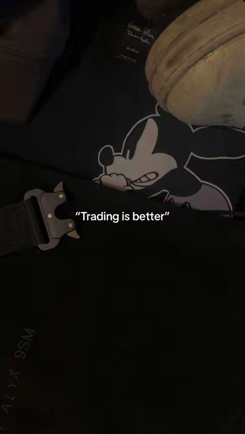 The cover image is a dimly lit, angled shot focusing on a person's attire, with a black jacket featuring a Mickey Mouse design, a metal belt buckle, and additional elements. A text overlay reads "Trading is better". The color scheme is dark, with a focus on black and grayscale.