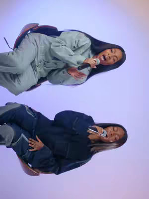 The cover image features two people, each in a dark outfit and another in light gray, likely in a studio setting. Each has a microphone. The background is a gradient of purple and blue.