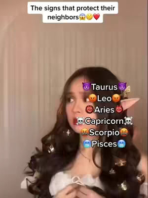 A young woman with long dark hair and an elf ear accessory is centered in the frame. Text overlays list zodiac signs with corresponding emojis, all set against a blurred background of light-colored walls. The woman has wide eyes and an expressive face.