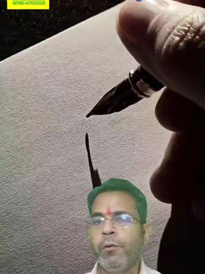 A man with glasses and a red mark on his forehead is in the bottom center of the image. Above him, a hand holds a fountain pen that is positioned to write on a white paper. The image has a warm, neutral color palette with the pen ink appearing black.