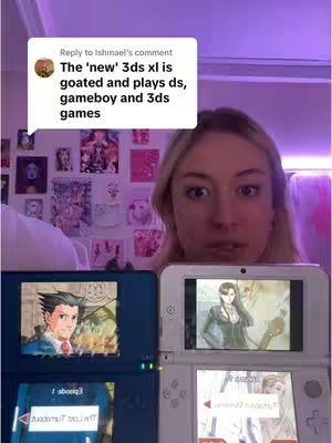 A woman with blonde hair looks directly at the camera. Behind her is a wall covered with pictures and posters. In her hands, she is holding and displaying two different Nintendo DS consoles, each with a game playing on the screen, suggesting a comparison or review of the consoles.