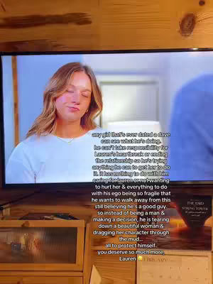 A woman is seen on a TV screen, eyes closed, likely in a moment of reflection. Text overlays the screen with a lengthy message judging a man's actions in the relationship. The background shows a blurred interior.
