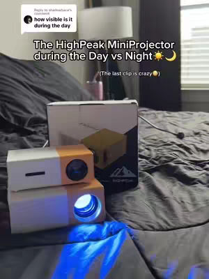 The cover image shows a bed with a gray bedspread. Two mini projectors are placed on the bed, along with their box. Text overlays describe the video's content.