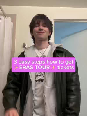 The video shows a young man in a casual indoor setting, likely a bathroom. He stands facing the camera with a neutral expression, wearing a white t-shirt under a grey hooded sweatshirt, and a dark green leather jacket. A pink banner with white text overlays the image, and a white shower curtain is visible to the left. The background includes a window, and the image uses a soft, natural lighting.