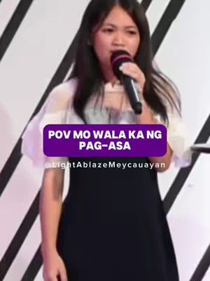 The cover image shows a young woman with dark hair holding a microphone and speaking. A purple banner overlay displays text. The background has a blurred white and dark striped pattern. She is wearing a black dress with sheer white sleeves.