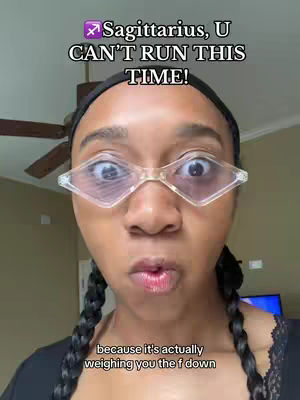 A selfie with a dark-haired woman wearing clear, diamond-shaped glasses. The foreground is dominated by the woman's face, with a surprised expression emphasized by wide eyes and pursed lips. The background includes a ceiling fan and a glimpse of a wall, suggesting an indoor setting.