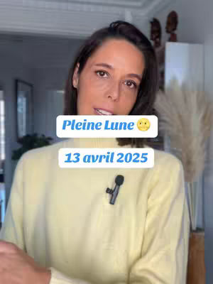 A woman with brown hair is centered in the frame, wearing a cream-colored sweater. Text overlays appear above and below her, with a light-colored background. A small lavalier microphone is clipped to her sweater. The overall composition has a soft, well-lit appearance.
