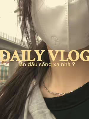 The cover image shows a close-up of a person wearing a face mask. The subject's hair is partially visible, and a portion of their clothing is visible. Text overlaid on the image reads "DAILY VLOG" and "lần đầu sống xa nhà ?".