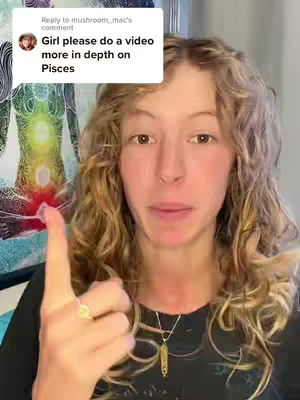 A woman with long, curly blonde hair is centered in the frame against a blurred background. She is wearing a black top and a gold necklace and has her right index finger raised. The image includes a comment box in the upper left corner with text.