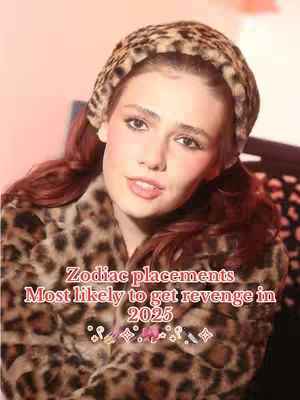 A woman with long, red hair and rosy cheeks poses with a soft smile, wearing a leopard-print headband and coat, set against a blurred, pink backdrop.