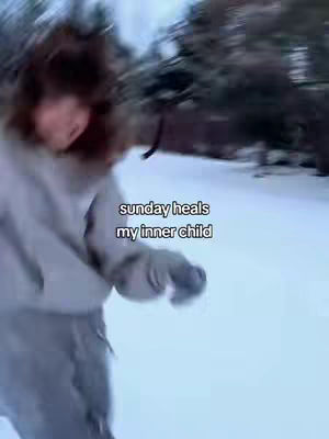 A person is running in a snowy environment, it is a bit blurry and out of focus. The person is wearing a hooded jacket and pants. Text overlay on image is 'sunday heals my inner child.'
