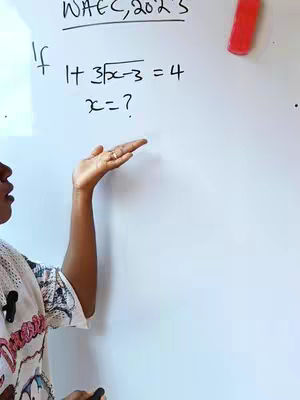 A woman is seen in a close-up shot, gesturing towards a whiteboard with a math equation written on it. The whiteboard has an equation written on it, written in black marker, with the top right area having a red pen or marker. The woman's face is partially visible, is focused on the maths question written on the board. Her arm is stretched out and her hand is pointing towards the whiteboard, and she wears white top.