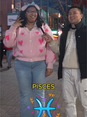 The cover image shows a woman standing in front of a man. She is wearing a pink cardigan with pink hearts, blue jeans, and a headband with ears. She is holding a microphone. The man is wearing a black jacket and white pants. There's a sign that says "PIECES" and the Pisces symbol.