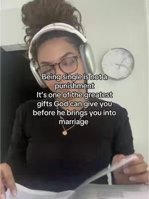 A woman with glasses and headphones is holding a book. Text overlays the image. A clock is on the wall behind the woman.