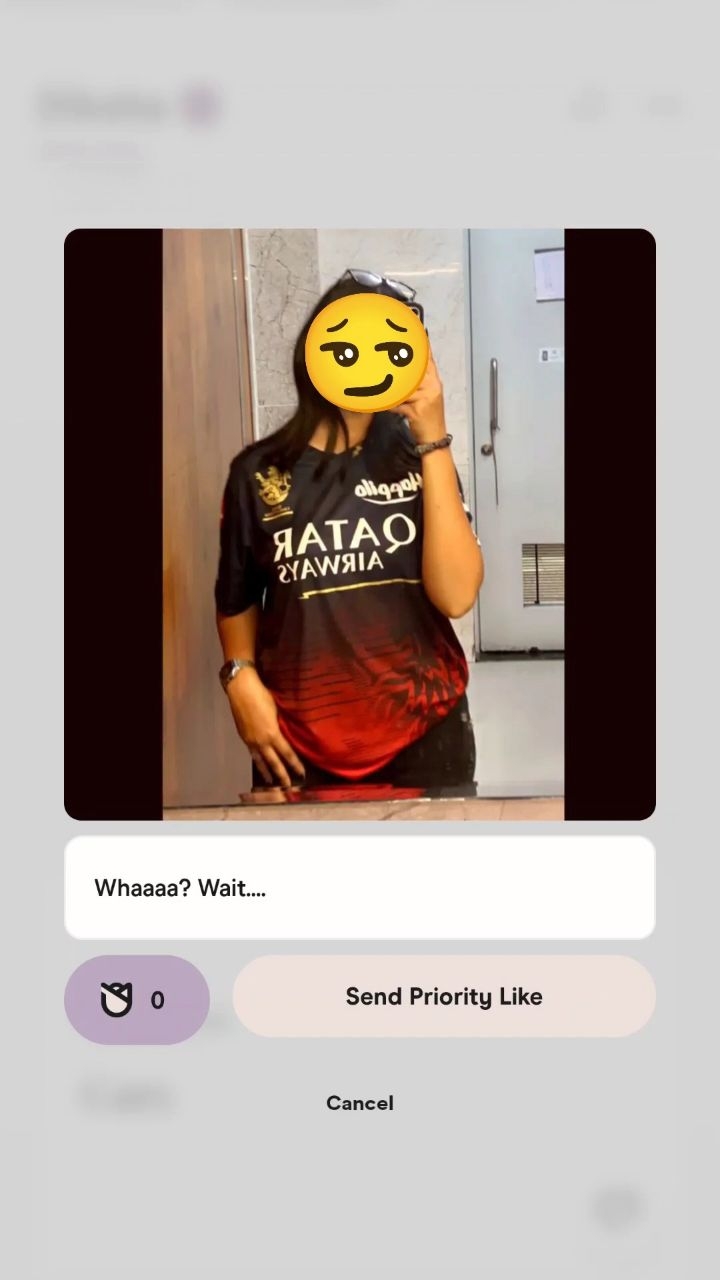 The cover image shows a person in front of a mirror, cropped from the waist up. They are wearing a jersey shirt with the word 'QATAR' in reverse. A yellow emoji face covers the person's actual face. Below the image is a white box that appears to show the image of a dating app, and below that are the texts 'Whaaaa? Wait.... Send Priority Like' and 'Cancel'.  The overall composition appears focused on a dating app interaction.
