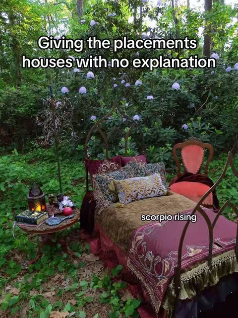 An outdoor scene features a wrought iron bed with ornate details and plush, colorful bedding, set amid lush greenery. The bed is positioned in a clearing surrounded by dense trees.