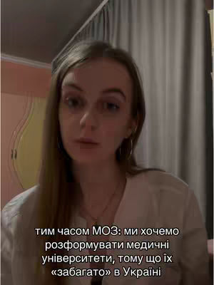A young woman with long blonde hair is centered in the frame, looking toward the camera. She is wearing a white top and a necklace. The background is a curtain and a wall. Text in Ukrainian is overlaid at the bottom.
