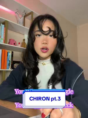 A young woman with dark hair and makeup is centered in the frame, looking directly at the camera with an open mouth. She is wearing a white top and a dark blue jacket. Text overlays are incorporated into a design element. Shelves of books are visible in the background.