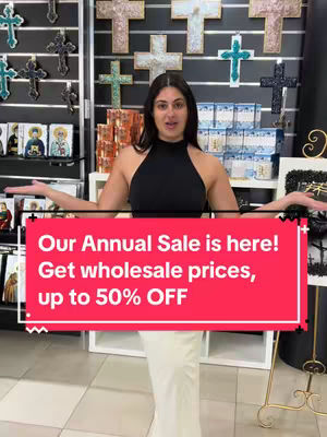 The cover image features a woman standing in front of a display of crosses and religious iconography. She has her arms outstretched, and a red banner with white text is overlaid on the image, advertising an annual sale.