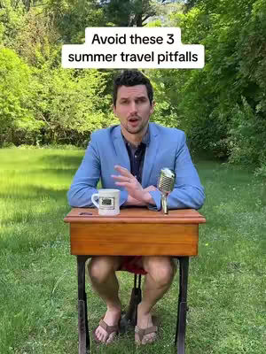A man in a blue blazer sits at a smallschool desk in a natural outdoor setting. The background features lush green foliage and grass. He is positioned behind the desk, with a microphone and a mug in front of him. A text overlay above the man reads 'Avoid these 3 summer travel pitfalls'.