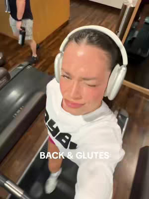 A first-person perspective, high-angle shot of a woman on a treadmill, winking at the camera. She's wearing headphones and a casual white t-shirt, with text overlayed on the image.
