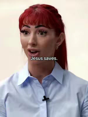 A medium shot features a woman with long red hair and a light blue collared shirt. The text "Jesus saves." is overlaid on the image. The background is a plain, light-colored wall.