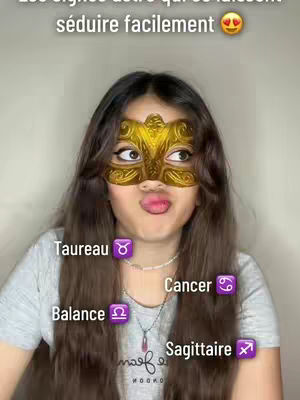 A young woman with long brown hair wearing a gold mask that covers her eyes and nose is posing for the camera. She is wearing a gray shirt, and the background is a plain light color. Text overlays indicate the zodiac signs Taurus, Balance, Cancer, and Sagittarius.
