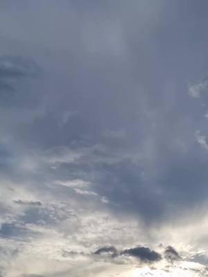 A cloudy sky fills the frame, with various shades of gray and white depicting the clouds. The light appears to be coming from the bottom right, highlighting the cloud formations and creating a dynamic and slightly darker atmosphere. The composition is simple, with a natural and peaceful feel.