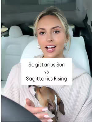 A woman with blonde hair is in the driver's seat of a car. A small dog is in her lap. A text overlay on the image reads "Sagittarius Sun vs Sagittarius Rising."