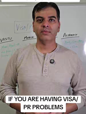 A medium shot of a man in a light-colored, long-sleeved shirt standing in front of a whiteboard. The man is looking towards the camera with a neutral expression. He has dark hair and a slightly receding hairline. On his shirt is a circular pin. Behind him, the whiteboard has handwritten text in the background. The bottom of the image has white text overlay.