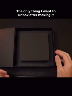 The cover image shows a pair of hands opening a black box to reveal a black object inside, possibly a product or a package. The lighting is neutral, and the focus is on the hands and the box.