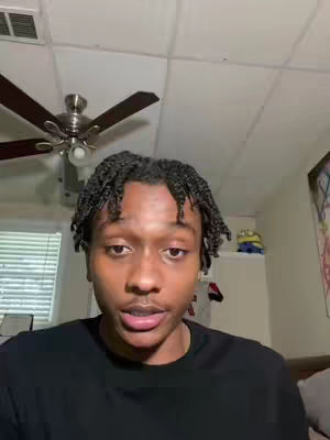 The cover image is a medium shot featuring a young Black man in a room with a ceiling fan. He's wearing a black shirt. The ceiling is white, and there is a fan in the center. The man is the main focus of the shot. The background includes a window, a wall, and some items like a Minion toy on a shelf.