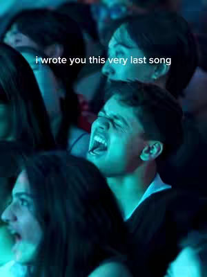 The cover image presents a mixed group of people at a concert. The focus is on a young man in the foreground, captured mid-scream with his mouth wide open. The shot is from a close-up perspective, above the crowd. The lighting is dim with a blue/greenish hue, suggesting a concert setting. There's text overlaid at the bottom of the image: I wrote you this very last song