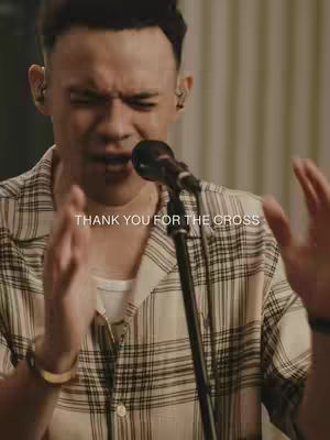 A man is singing into a microphone, with the words "THANK YOU FOR THE CROSS" overlaid on the bottom of the image.