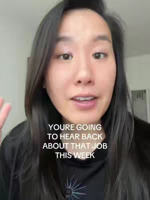 A woman with long black hair is centered in the frame, looking directly at the camera and speaking. Text overlays appear on the lower portion of the frame.