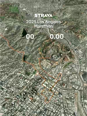 An aerial perspective of a city, possibly Los Angeles, with a marathon course route overlaid in orange tracing the streets. The Strava logo and marathon details are prominently displayed.