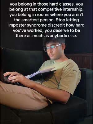 A young man with glasses sits on a dark green couch, facing a laptop. He holds a notepad and pen in his lap. The background is a wood-paneled wall, with text overlayed on the image in a white font.