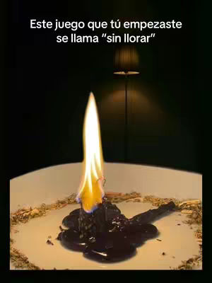 An image of a candle flame burning on a dark background. The candle sits in a white bowl, surrounded by some kind of dark substance. The flame is tall and bright yellow and orange.