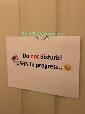 A photograph of a white piece of paper attached to a beige door. Written on the paper in black are the words "Do not disturb! USRN in progress.." with a winking face emoji. A small image of the american flag is to the left of the words. On top of the paper in green text is the phrase, "My NCLEX journey..“