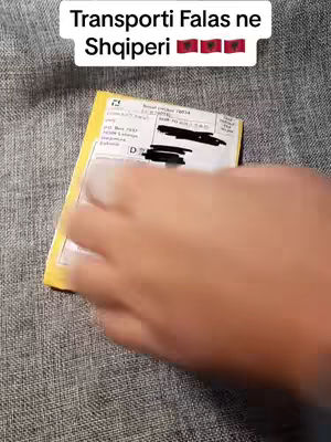 The cover image shows a hand holding a yellow envelope with a shipping label against a gray background. Above the envelope is a white text box, which reads "Transporti Falas ne Shqiperi" with three Albanian flags to its right. The hand obscures some of the envelope.
