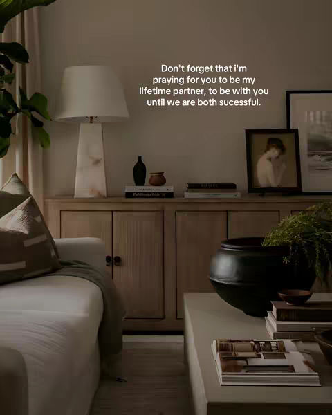 A well-lit room with neutral tones, featuring a white sofa, wooden furniture, lamp, books and decorations, a framed painting enhancing a calm and comfortable ambiance. Text overlayed.