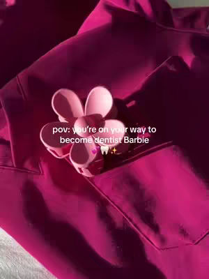 The cover image features a close-up shot of a magenta-colored shirt or fabric. A pink flower-shaped hair clip is prominently displayed, centered on the material. The composition is simple, with the focus on the texture and color of the fabric, and the decorative hair accessory.