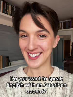 A woman with short brown hair smiles at the camera. She is wearing a cream-colored sweater, and text reading "Do you want to speak English with an American accent?" is overlaid on the bottom of the image.