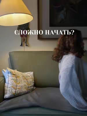 The cover image shows an interior scene. A woman is seated on a green sofa, her back to the camera, wearing a white sweater. A patterned pillow rests on the sofa next to her. A lamp and artwork hang on the wall, creating a warm atmosphere. Text overlayed at the top indicates the main subject of the video.