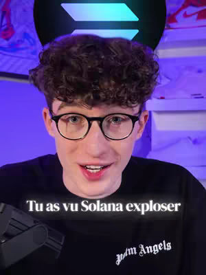 A young man with curly brown hair and glasses is centered in the frame, with a blurry background. Overlaid text at the bottom states, 'Tu as vu Solana exploser'. The man is wearing a black t-shirt, and the image has a slightly purple hue.